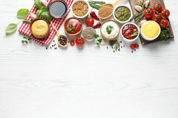 Composizione flat lay con diverse salse e spazio per il testo su sfondo bianco in legno — Foto Stock