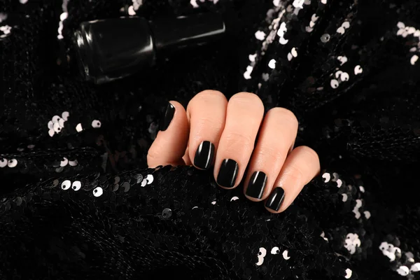 Femme avec manucure noire tenant tissu brillant, gros plan. Tendances du vernis à ongles — Photo