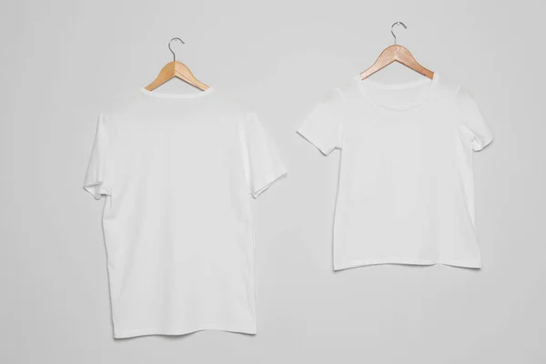 Appendini con t-shirt bianche su sfondo grigio. Finto per il design — Foto Stock