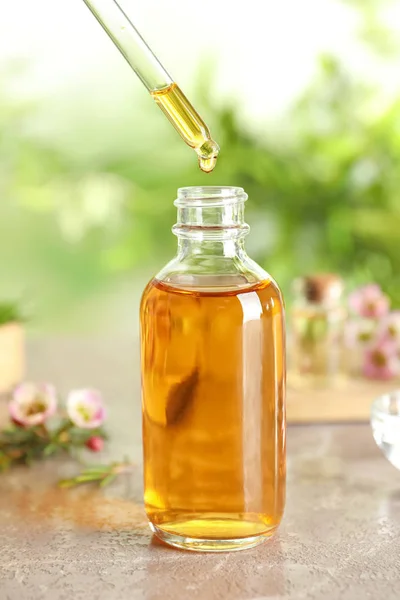 Despejar óleo essencial de árvore de chá natural em garrafa na mesa — Fotografia de Stock
