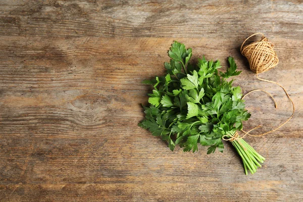 Bunch of fresh green parsley and twine on wooden background, flat lay. Space for text