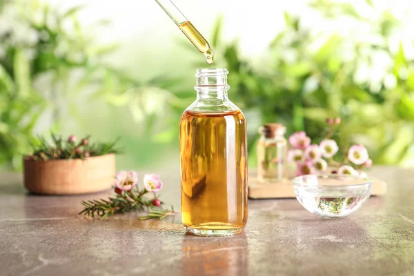 Druipende natuurlijke Tea tree etherische olie in fles op tafel — Stockfoto