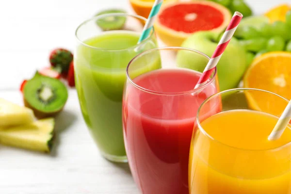 Glas olika juicer med halmstrån och färsk frukt på trä bord, närbild. Utrymme för text — Stockfoto