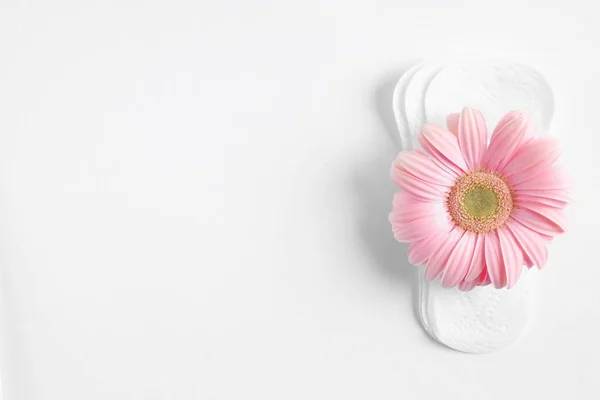 Cuscinetti mestruali e fiori di gerbera su sfondo bianco, vista dall'alto. Cura ginecologica — Foto Stock