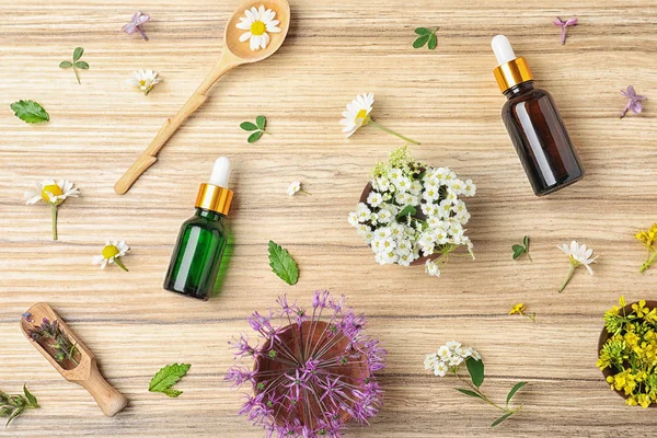 Composición plana con aceites esenciales y flores sobre mesa de madera —  Fotos de Stock