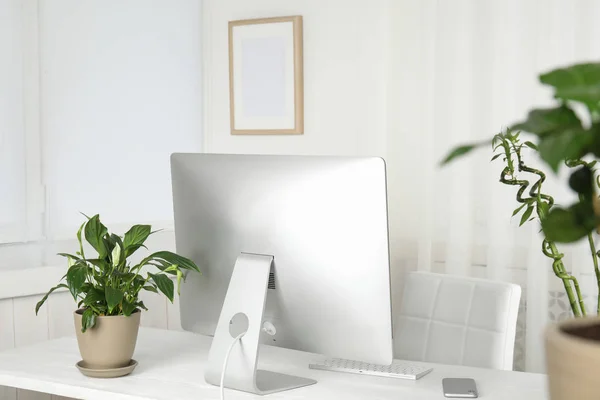 Interior de la oficina con plantas de interior y monitor de computadora en la mesa —  Fotos de Stock