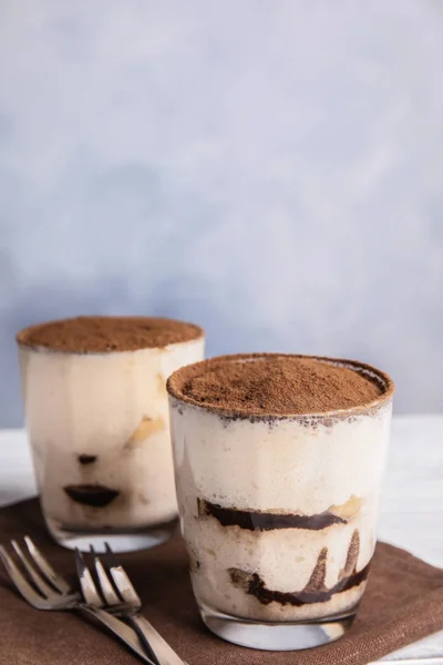 Two glasses of tiramisu cake on table against color background, space for text — Stock Photo, Image
