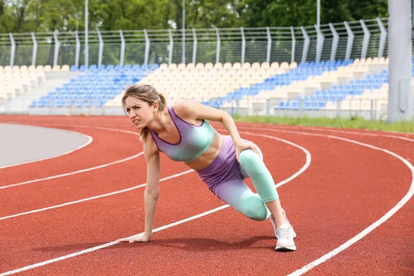 Femme en tenue de sport souffrant de douleurs au genou au stade — Photo