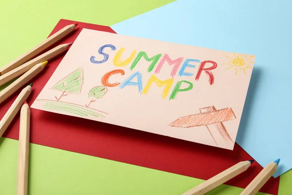 Papel com texto escrito SUMMER CAMP, desenhos e diferentes lápis sobre fundo de cor, close-up — Fotografia de Stock