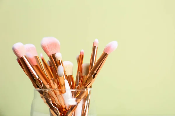 Jar met make-up borstels tegen kleur achtergrond. Ruimte voor tekst — Stockfoto