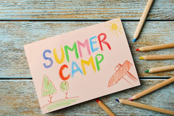 Papier z tekstem pisemnym Summer Camp, rysunki i różne ołówki na drewnianym tle, widok z góry — Zdjęcie stockowe