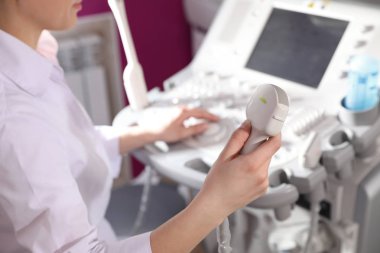 Sonographer holding ultrasound machine probe in clinic, closeup clipart