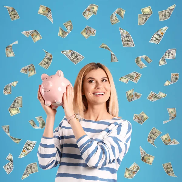 Mujer feliz con alcancía y dinero volando sobre fondo de color — Foto de Stock