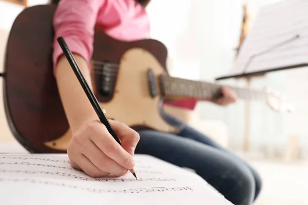 Criança com guitarra escrevendo notas de música em casa, close-up — Fotografia de Stock