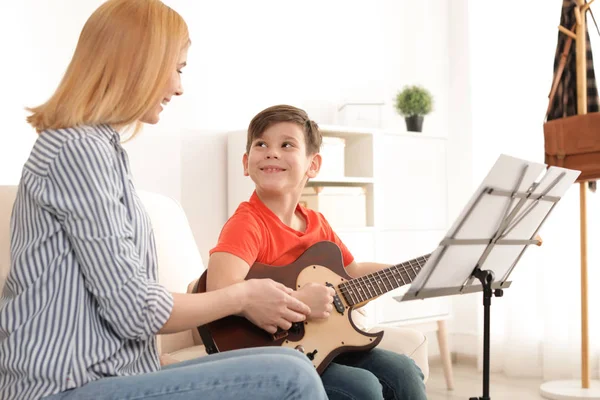 Mały chłopiec gra na gitarze z nauczycielem na lekcji muzyki. Notatki edukacyjne — Zdjęcie stockowe