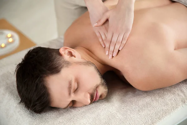 Bonito homem recebendo massagem de volta no salão de spa — Fotografia de Stock