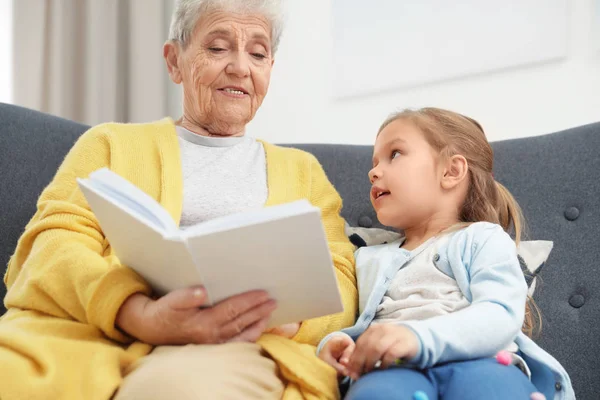 Fille mignonne et sa grand-mère lecture livre à la maison — Photo