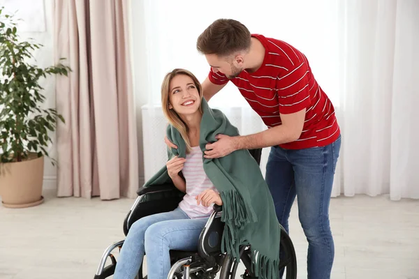 自宅でチェック柄で車椅子の女性をカバーする男。無効にする — ストック写真