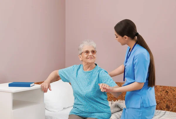 Verpleegkundige bijstaan Senior vrouw op bed in ziekenhuis Ward — Stockfoto