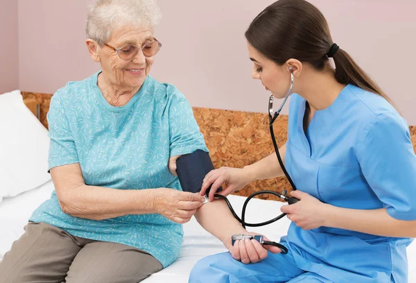 병원 병 동에 있는 고위 여자의 혈압을 측정 하는 간호 원. 의료 지원 — 스톡 사진