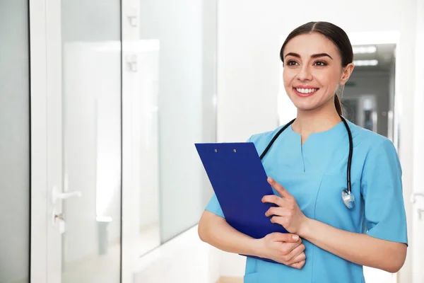 Retrato de enfermera con portapapeles en el pasillo del hospital. Asistencia médica — Foto de Stock