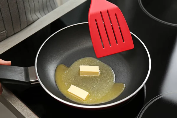 Woman stirring melted butter in frying pan on stove, closeup — Stock Photo, Image