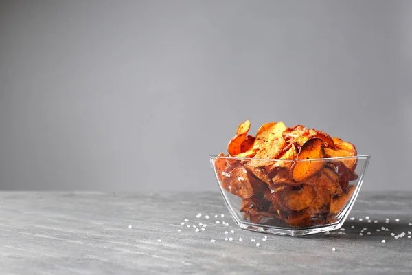 Cuenco de batatas fritas y sal sobre la mesa sobre fondo gris. Espacio para texto —  Fotos de Stock