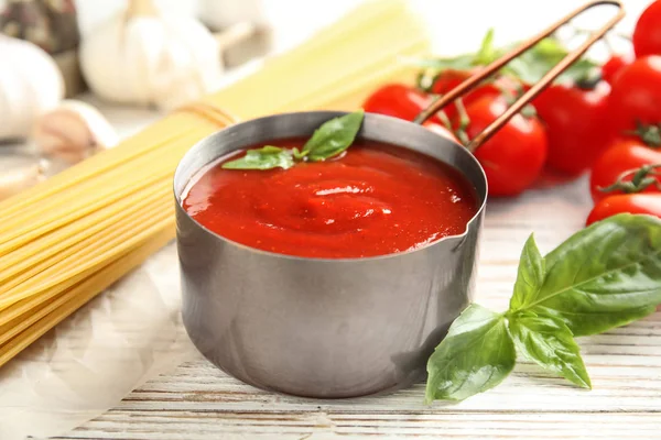 Casserole de sauce tomate savoureuse servie sur une table en bois — Photo