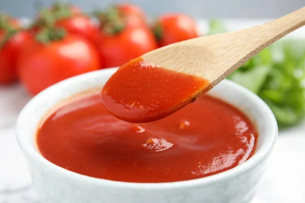 Löffel mit Tomatensauce über Schüssel, Nahaufnahme — Stockfoto