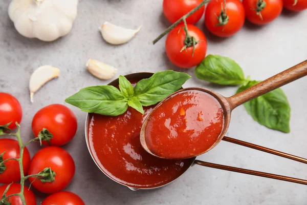 Vlakke lay samenstelling met lepel en pan van tomatensaus op grijze lijst — Stockfoto