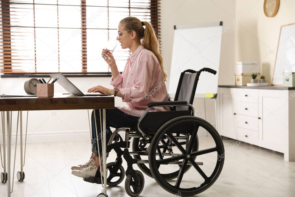 Woman in wheelchair drinking water at workplace
