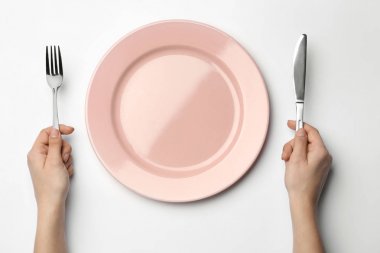 Beyaz arka planda çatal, bıçak ve boş plaka ile kadın, üst görünüm
