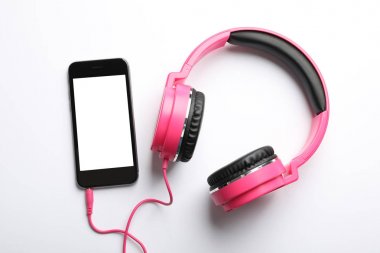 Şık kulaklıklar ve beyaz arka planda modern telefon, üst görünüm. Metin alanı