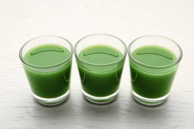 Beyaz ahşap arka planda gözlük taze Buğday çim suyu