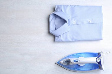 Düz katlanmış temiz gömlek ve ışık masasında modern demir ile kompozisyon yatıyordu. Metin alanı