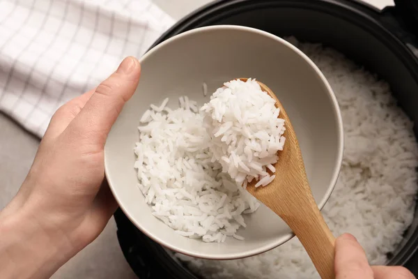 Wanita menempatkan nasi ke dalam mangkuk dari kompor di dapur, pandangan atas — Stok Foto