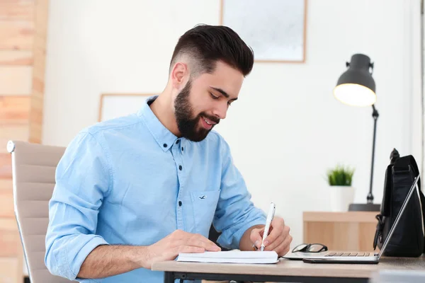 Beau jeune homme travaillant à table au bureau à domicile — Photo