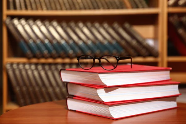 Hromádka knih a brýlí na stole v knihovně. Místo pro text — Stock fotografie