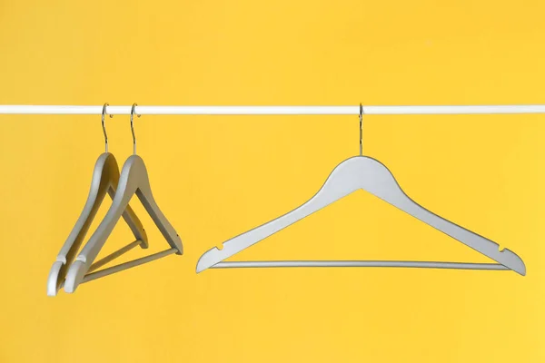 Metal rack with clothes hangers on color background — Stock Photo, Image