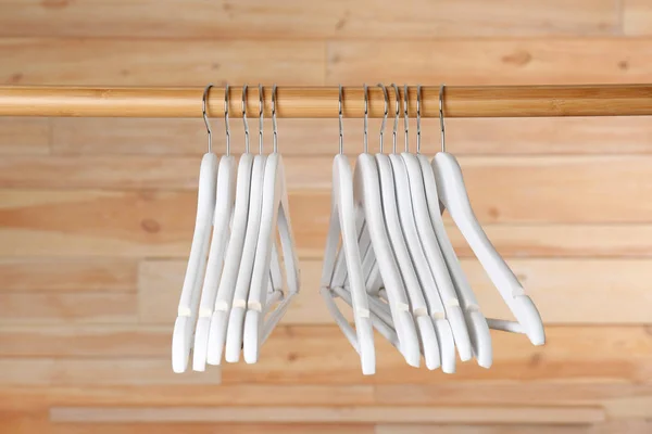 Rack with clothes hangers on wooden background — Stock Photo, Image