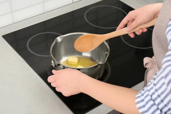 Femme remuant du beurre dans une casserole sur une cuisinière électrique, gros plan — Photo