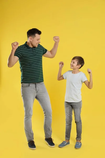 Portrait of emotional dad and his son on color background — Stock Photo, Image