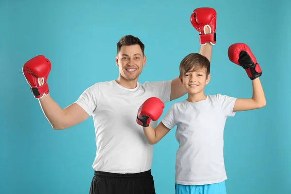 Papá emocional y su hijo con guantes de boxeo sobre fondo de color — Foto de Stock