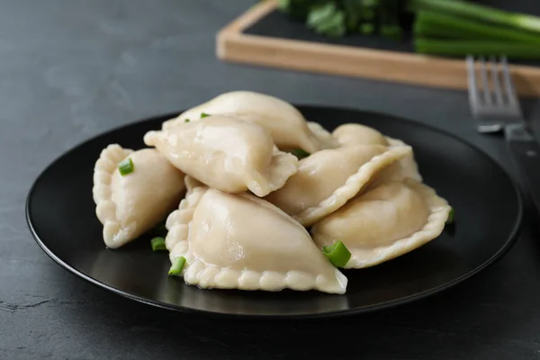 Tallrik med läckra dum Plings serveras med grön lök på bordet — Stockfoto