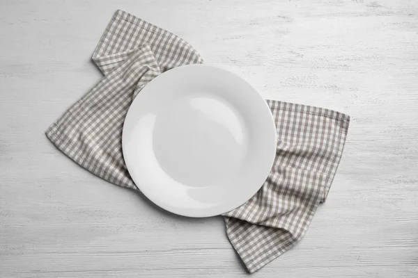 Empty plate and napkin on white wooden background, flat lay — Stock Photo, Image