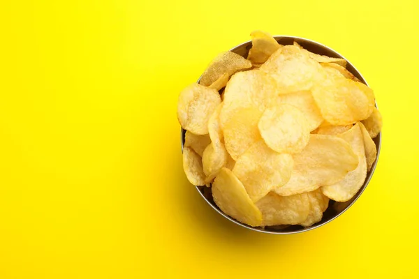 Heerlijke knapperige aardappelchips in kom op kleur achtergrond, bovenaanzicht met ruimte voor tekst — Stockfoto