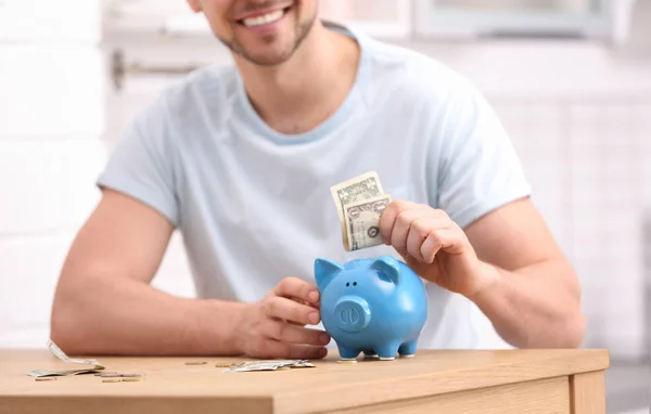 Man with piggy bank and money at home, closeup — Stock Photo, Image