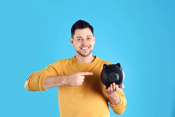 Man with piggy bank on color background — Stock Photo, Image