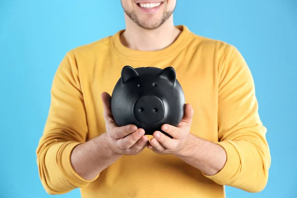 Man with piggy bank on color background, closeup — Stock Photo, Image