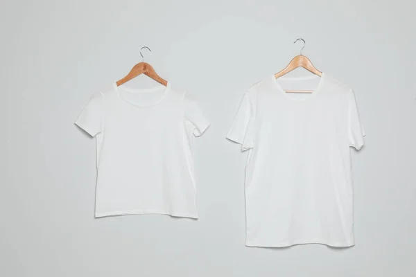 灰色の背景に空白のTシャツを持つハンガー。デザインのモックアップ — ストック写真